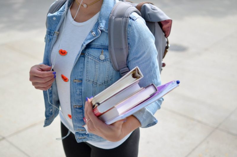 Female student in denim jacket holding books