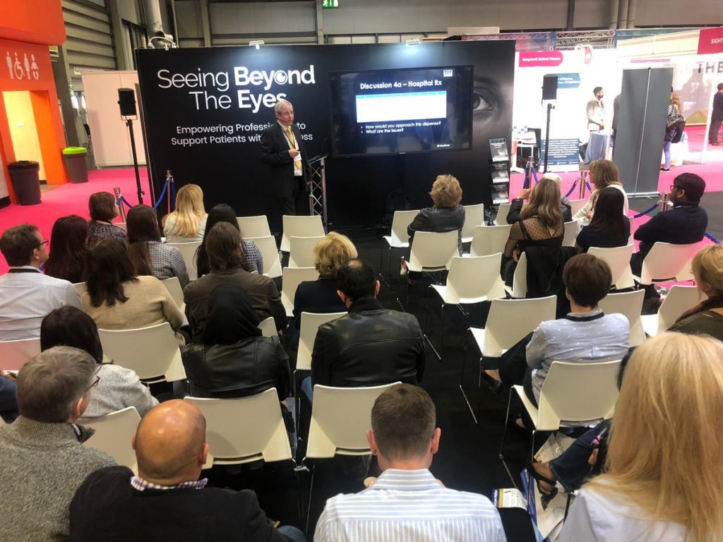 Peter Black on stage presenting to attendees in the Seeing Beyond the Eyes Zone at Optrafair