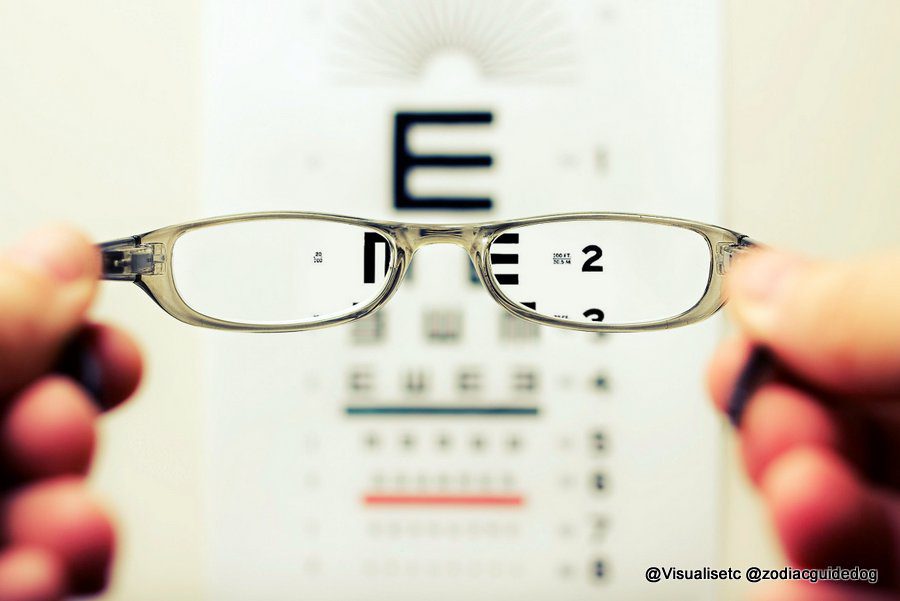 Looking through specs at an eye test chart