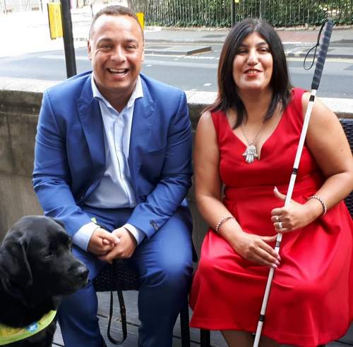 Man and woman laughing with guide dog