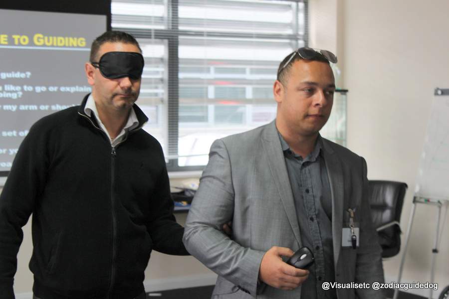 A Visualiase trainer guiding delegate who is wearing a blindfold