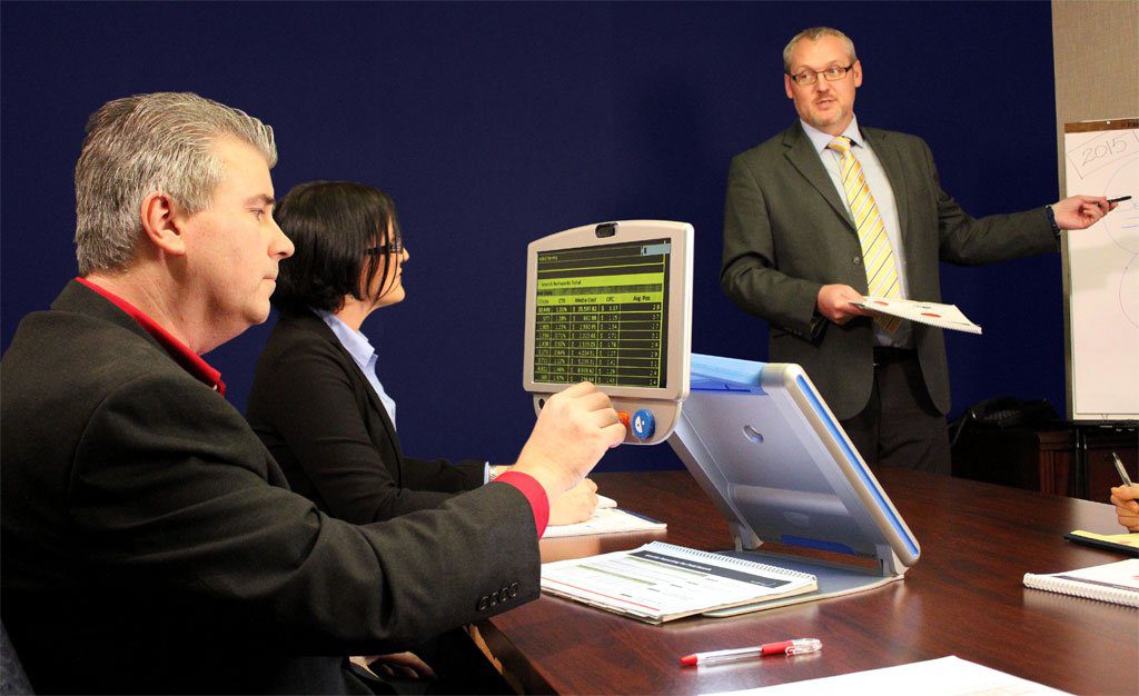Employee with visual impairment in a meeting using assistive technology to read a document