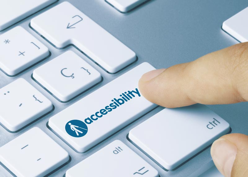 Finger pressing a laptop key entitled accessibility -it asl has a logo of a person using a white cane on it